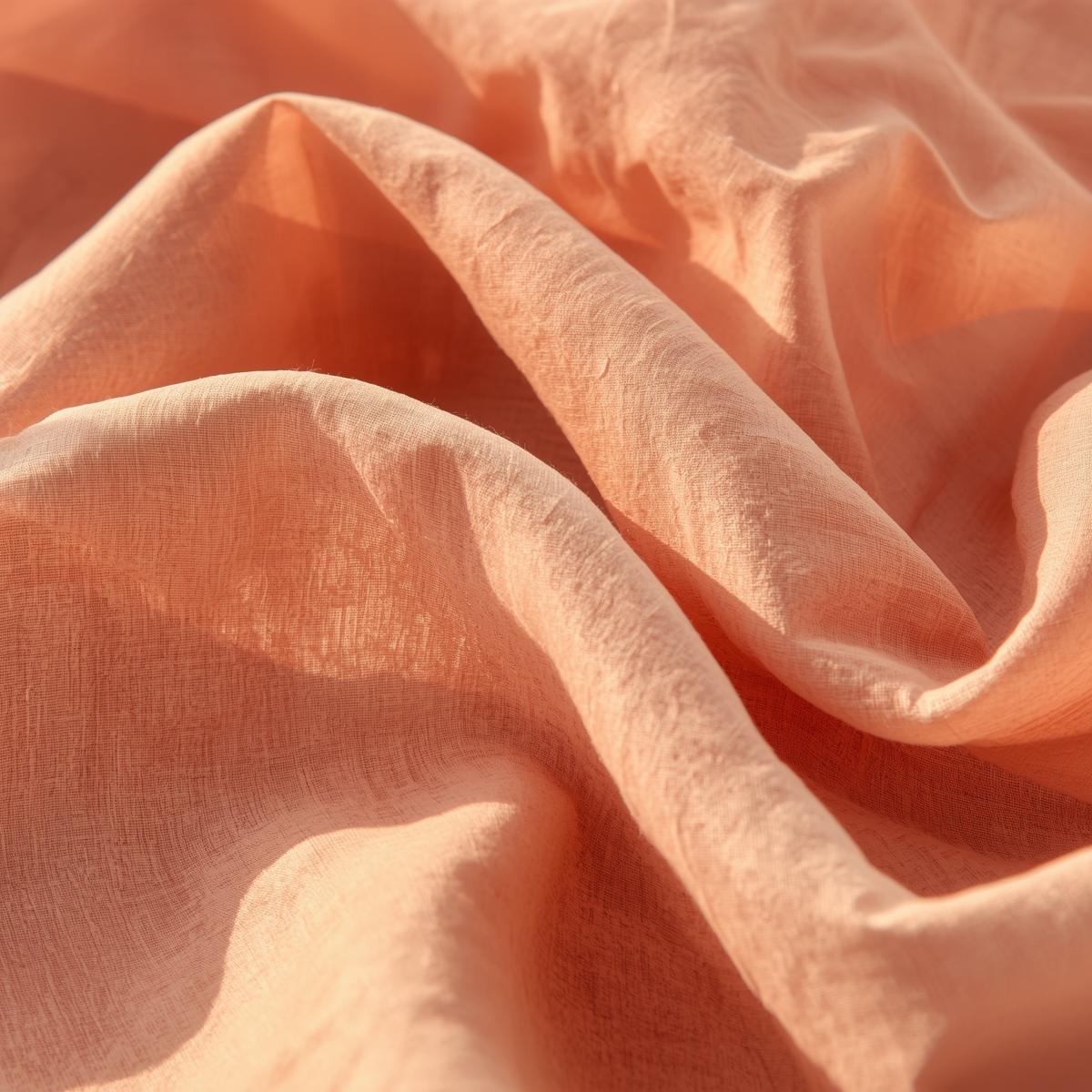flowing cotton muslin fabric, soft salmon colored lightweight cotton cloth with gentle folds, natural sunlight, organic textile photography
